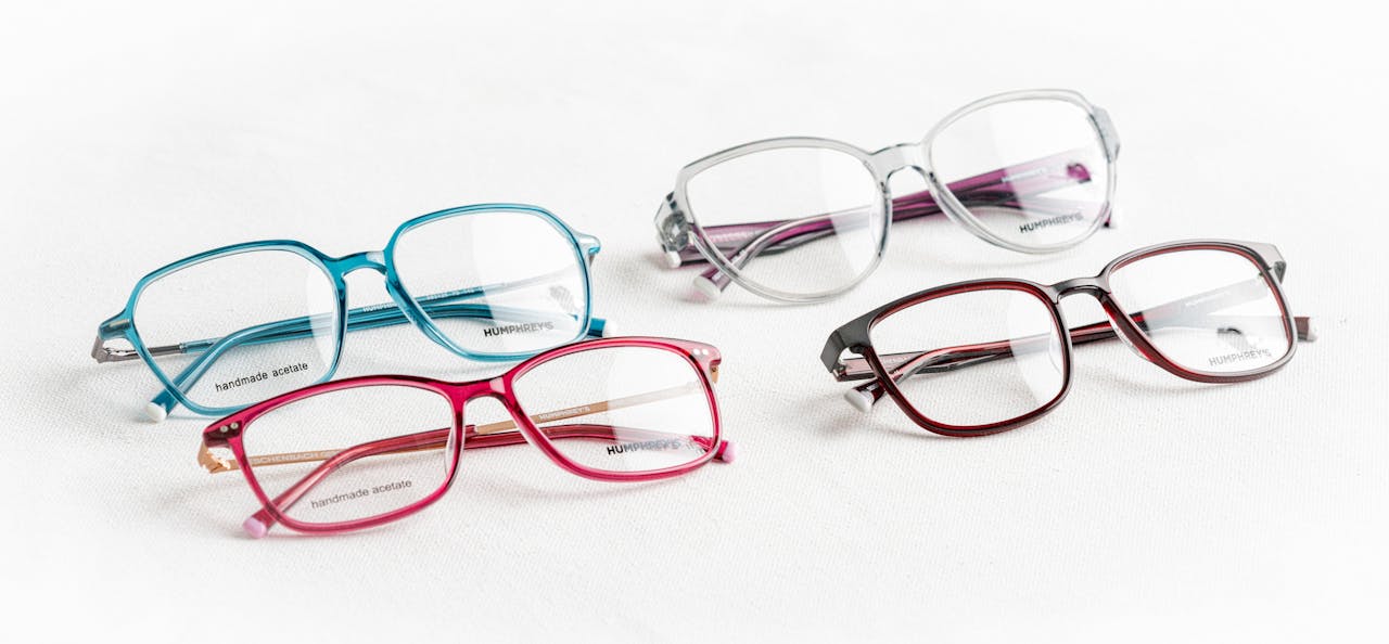 A collection of four colorful glasses on a white surface showcasing fashionable eyewear styles.