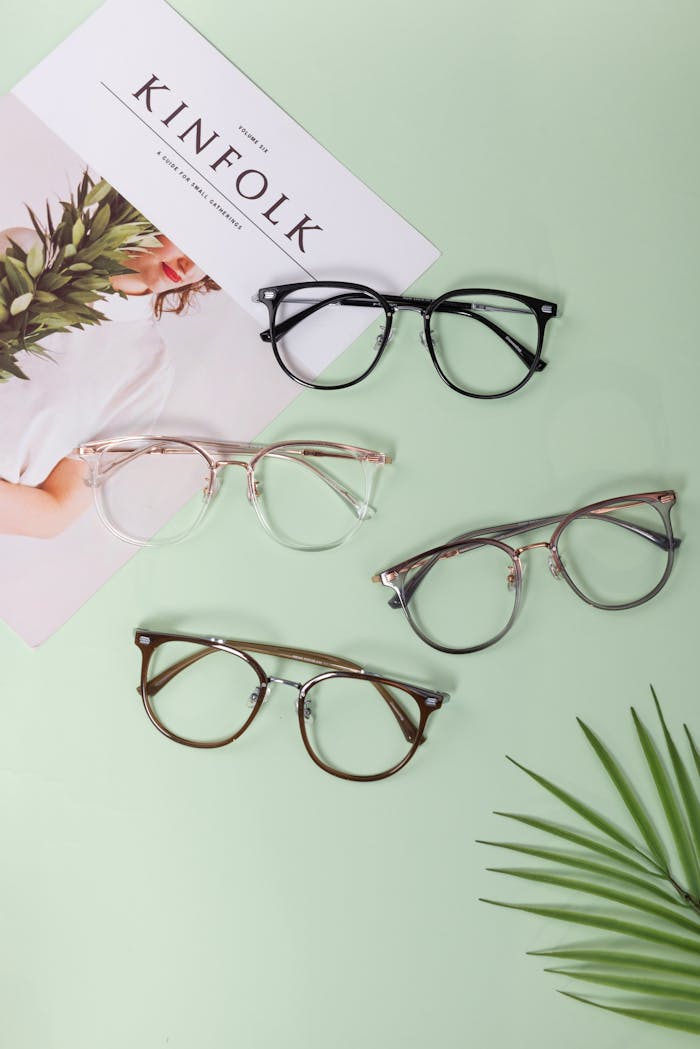 A modern flat lay of various glasses on a mint green backdrop with a magazine.